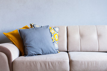 Multi-colored pillows on a beige fabric sofa, the concept of home comfort and cozy, copy space, close up