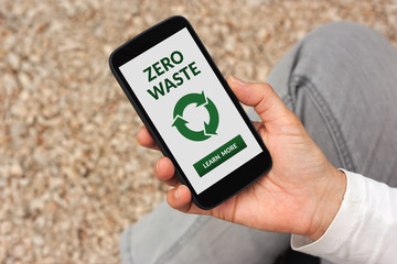 Hand holding smart phone with zero waste concept on screen. All screen content is designed by me