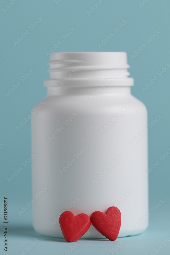 Wall mural Tablets in the form of heart and a jar for tablets on a blue background