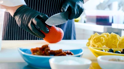 Chef cutting tomato for preparing italian food