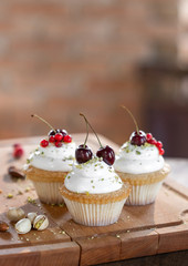 cupcakes or muffins with marshmallows of cherries and raspberries, sprinkled with nut crumbs on a wooden board. Sweets for the holiday.