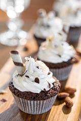 cupcakes or muffins with almonds and chocolate on a wooden board, copy space