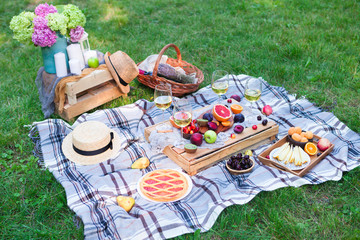 Picnic background with white wine and summer fruits on green grass, summertime party