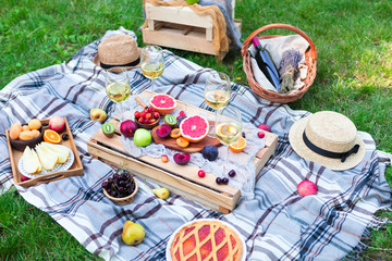 Picnic background with white wine and summer fruits on green grass, top view