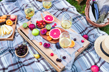 Picnic background with white wine and summer fruits on green grass, summertime party