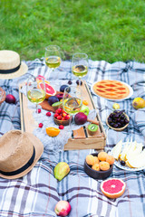 Picnic background with white wine and summer fruits on green grass, summertime party