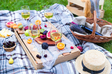 Picnic background with white wine and summer fruits on green grass, summertime party