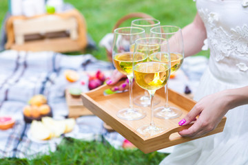 Young woman holding a dish with glasses white wine at picnic summer party, close up