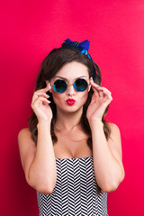 The girl in a red dress on a red background in the studio