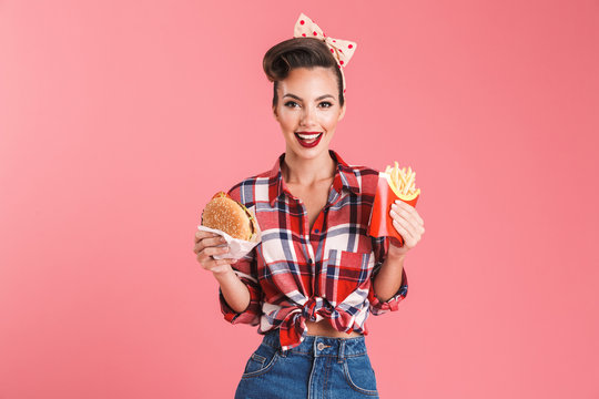 Young pin-up woman holding french fries and burger.
