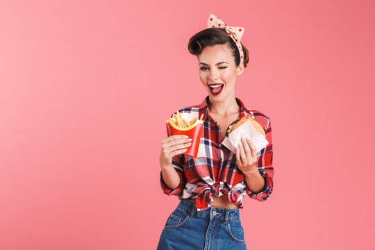 Young pin-up woman holding french fries and burger.