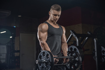 Fototapeta na wymiar Attractive tall muscular bodybuilder doing heavy deadlifts in moder fitness center.