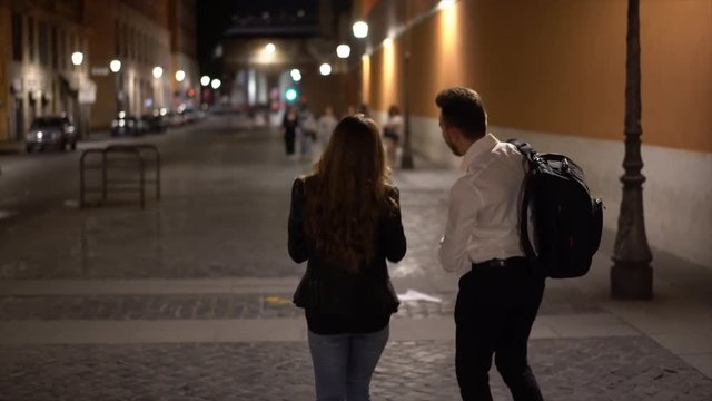 A young lovers traveller couple walks at summer night on a European street in Rome, Italy . Travel concept POV