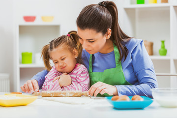 Mother and daughter are making cookies in their kitchen. 