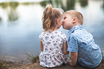 Your Happy Kids, Girl And Boy Are Sitting Near Lake