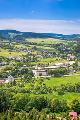 Fototapeta na wymiar Aerial view of rural scenery in the valley with green town and houses on foothills