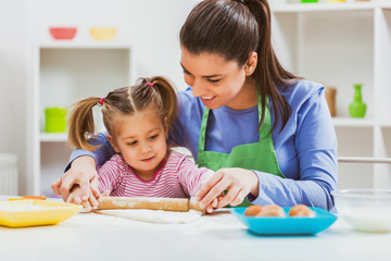 Happy mother and daughter are making cookies in their kitchen. 