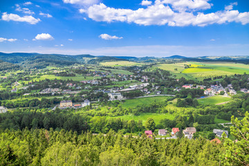Fototapeta na wymiar Countryside landscape in the valley, panoramic view of town with houses on foothills with green forest