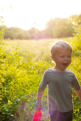 Fototapeta premium Little boy in summer sunny day holding toy in hands and running.