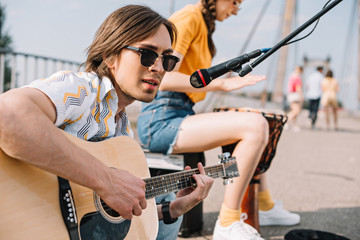 Young and happy male guitarist and female singer in city