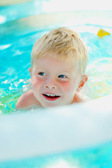Fototapeta na wymiar Portrait of baby boy enjoying swimming in inflatable pool
