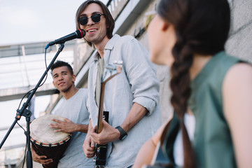 Multiracial young happy people performing and singing on street