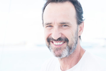 Handsome senior man traveling on sailboat and smiling happy and confident