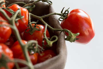 Pomodori freschi maturi su gambo dentro a cestino di stoffa