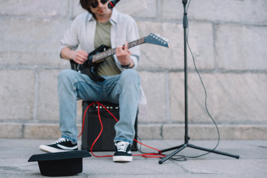 Empty Hat In Front Of Busker Playing Guitar And Singing In Urban Environment