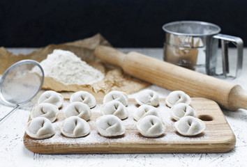 The process of making home-made dumplings. Raw homemade dumplings on a wooden board.