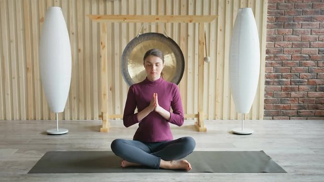 Sportive beautiful woman meditating in lotus pose sitting on the floor in studio
