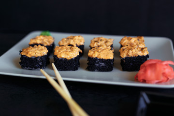 Rolls on a white plate on a black background with ginger and vassabi