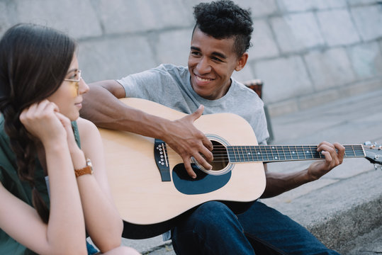 Multiracial Young People Playing Guitar And Singing On Street