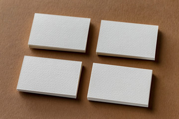 Mockup of four white business cards stacks at brown craft textured paper background.
