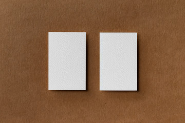Top view mockup of two white business cards at brown craft paper background.
