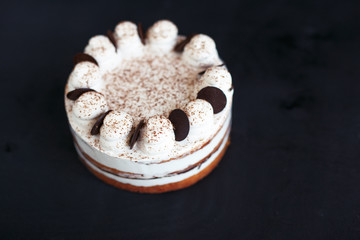 Naklejka premium White sponge cake with chocolate on a black background