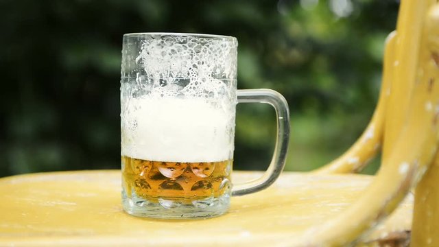  Fresh beer pouring into glass standing on an old chair at outdoor party