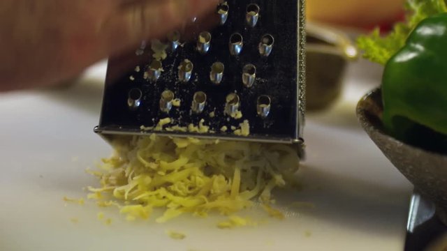 Tilt down shot of hands of unrecognizable cook grating cooked potato on kitchen countertop