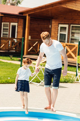 happy father and daughter going down into swimming pool