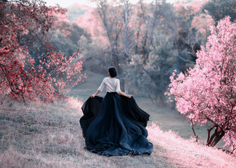 Princess in a vintage dress escapes. Walk through the picturesque autumn hills at sunset in pink...