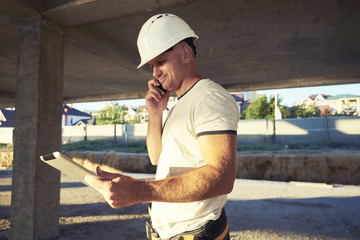 Happy handsome builder doing a call gesture with hand while holding touch pad. Business man or...