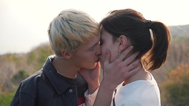 Young couple kissing outdoor close-up.