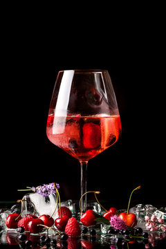 berry cold cocktail with alcohol in a glass crystal glass on a black background with berries, raspberries, strawberries, cherries, with ice. background image. Copy space, selective focus