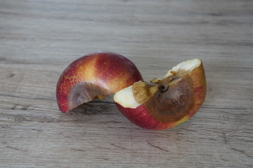 Rotten apple served on a white plate sliced in half
