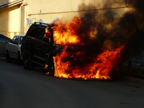 Burning car in the parking lot. Car catching fire, after act of vandalism or road incident © Svetalik