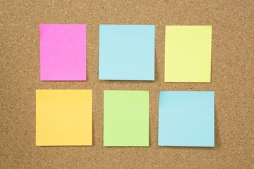 collection of colorful post it. paper note reminder sticky notes on cork bulletin board.  empty...