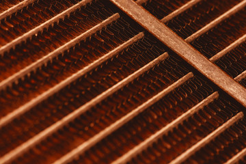 Lattice texture of old rusty radiator with copy space. Background of automotive radiator close-up. Abstract artwork with auto part in macro.