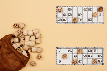 Wooden lotto barrels with bag and game cards on beige background