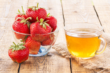 Glass cup of green tea and red ripe strawberries in glass bowl