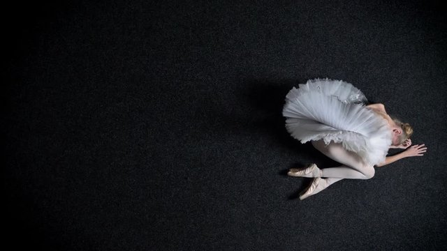 Silhouette of young girl ballerina is laying on floor, sadness, tiredness, ballet concept, top shot